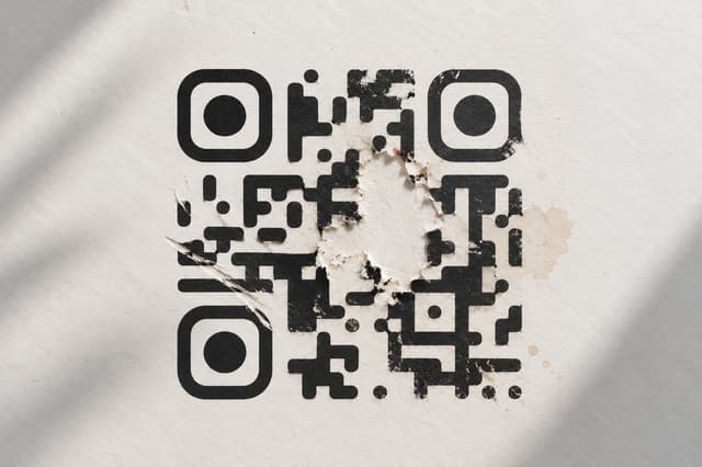 A damaged QR code with part of its pattern missing while remaining readable